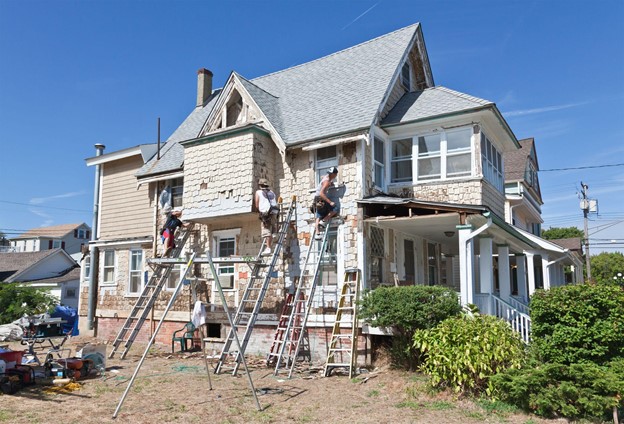 Green Remodeling Workers Outside Repair House